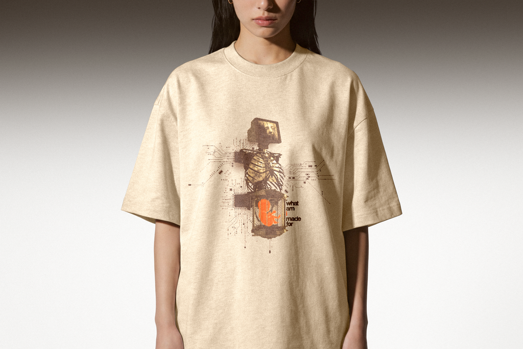 Person wearing a beige t-shirt with a graphic design on a plain background